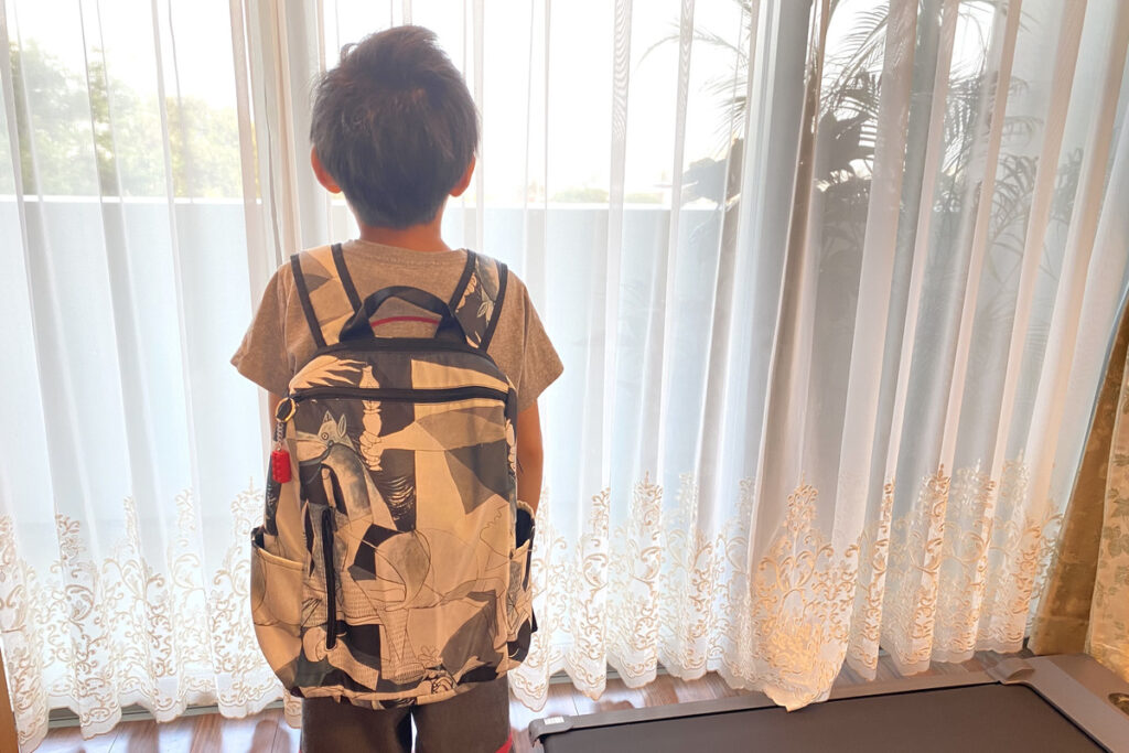 ピカソの「ゲルニカ」柄のリュックを背負う男の子。夢に向かって歩き出す後ろ姿。