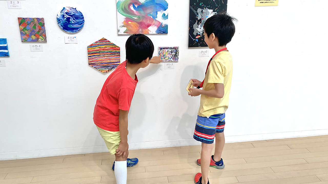 絵の前で友達に作品の意味を説明するAKASHI