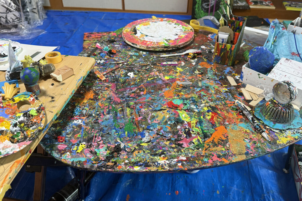 絵の具が重なり合い、カラフルに染まったAKASHIの作業机の上