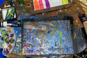カラフルな絵の具で覆われた机の上と使用中のアート用品