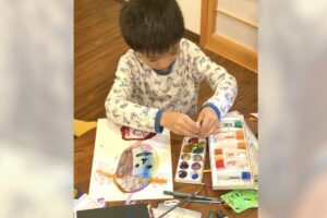 絵の具セットを前に、真剣に絵を描くAKASHIの姿