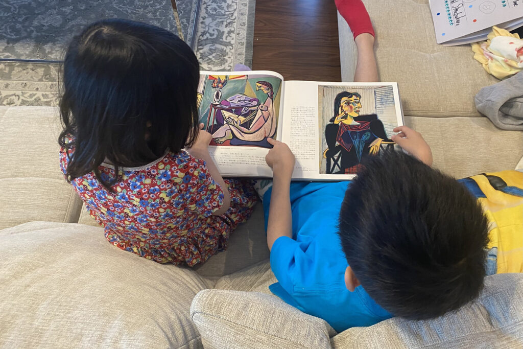ソファに並んでピカソの画集を見ている兄妹