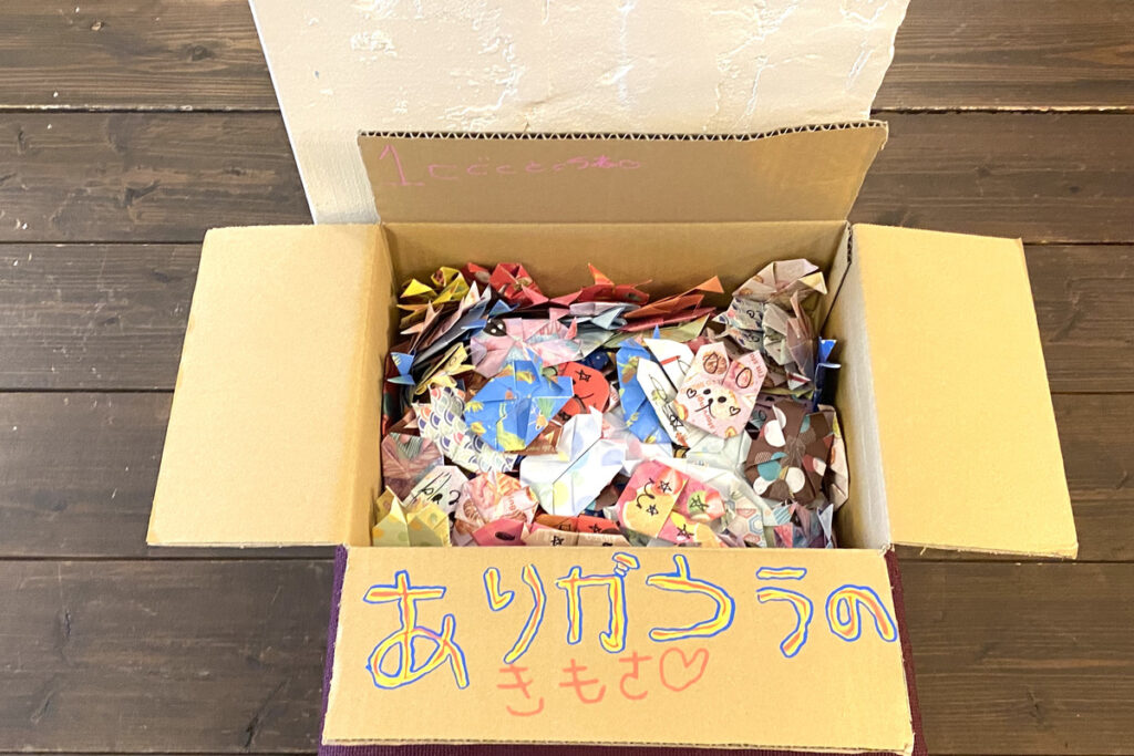 折り紙で作られたたくさんのうさぎが入った箱。『ありがとうのきもち』と書かれている