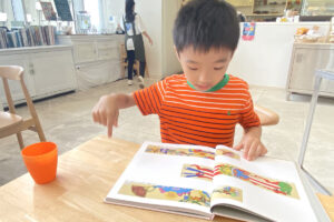 カフェでジミー大西の画集を夢中で眺めるAKASHI