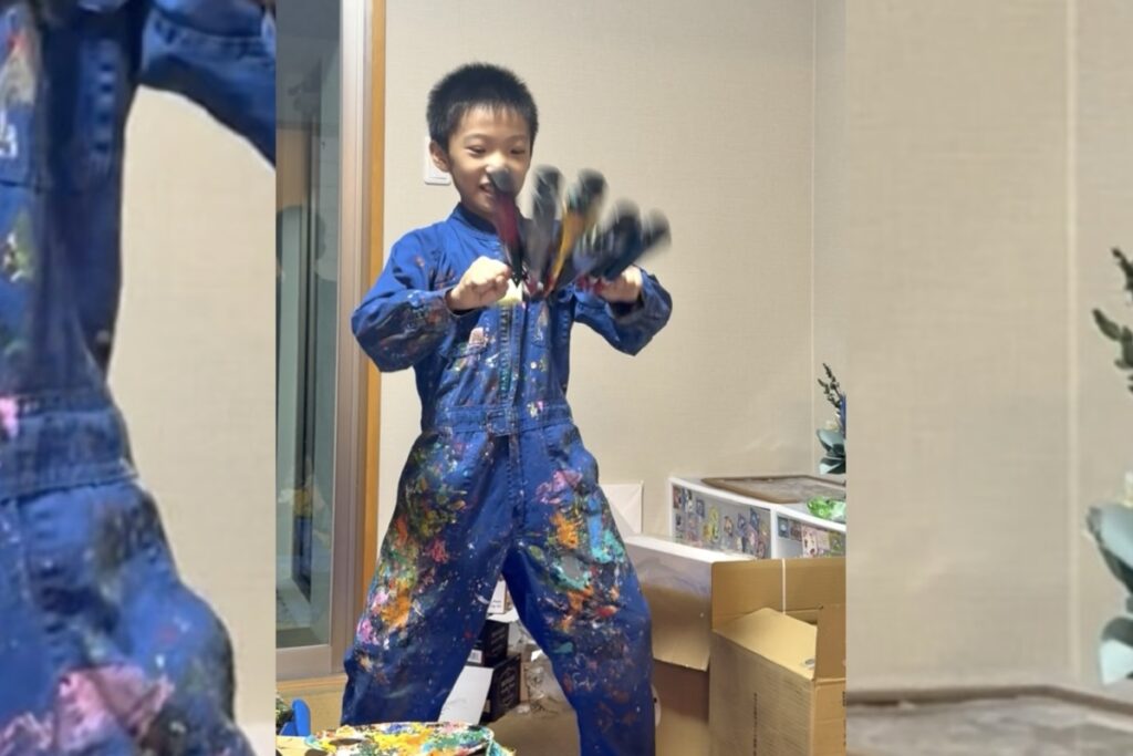 絵の具でカラフルになったつなぎを着て笑顔を見せるAKASHI