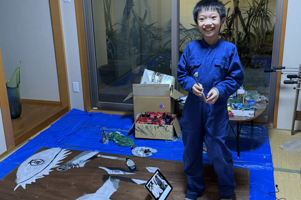 新品の青いつなぎを着て制作を始めるAKASHI