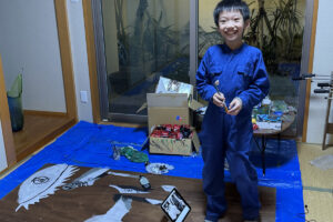 新品の青いつなぎを着て制作を始めるAKASHI