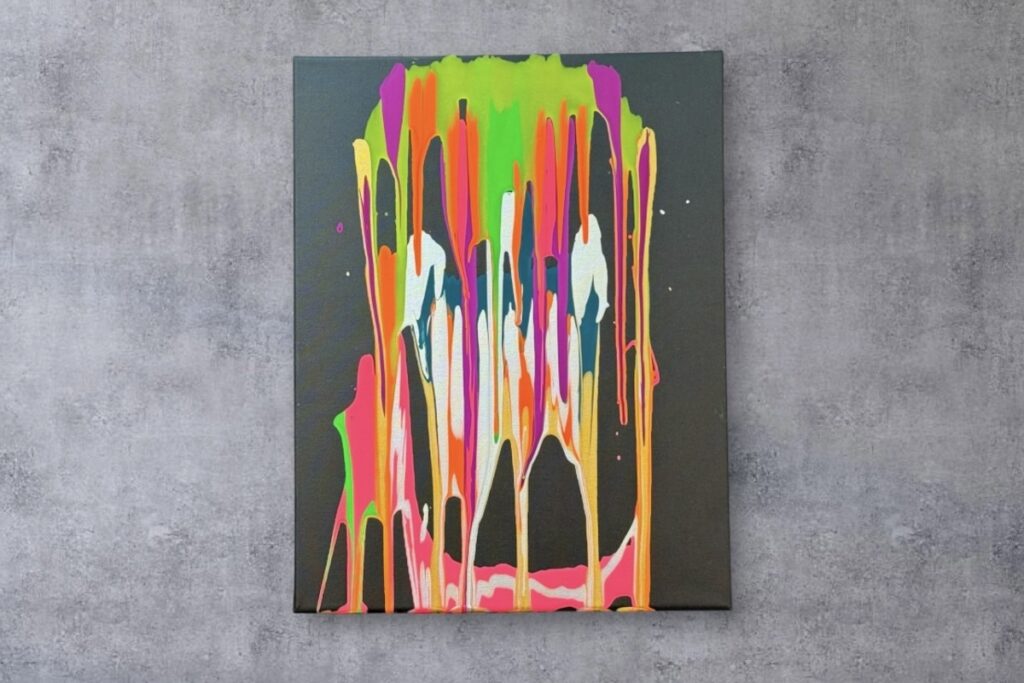 黒いキャンバスに蛍光のピンク・オレンジ・グリーン・ブルーの絵の具が垂れ、顔のように見える抽象画「とろとろ溶けた顔」