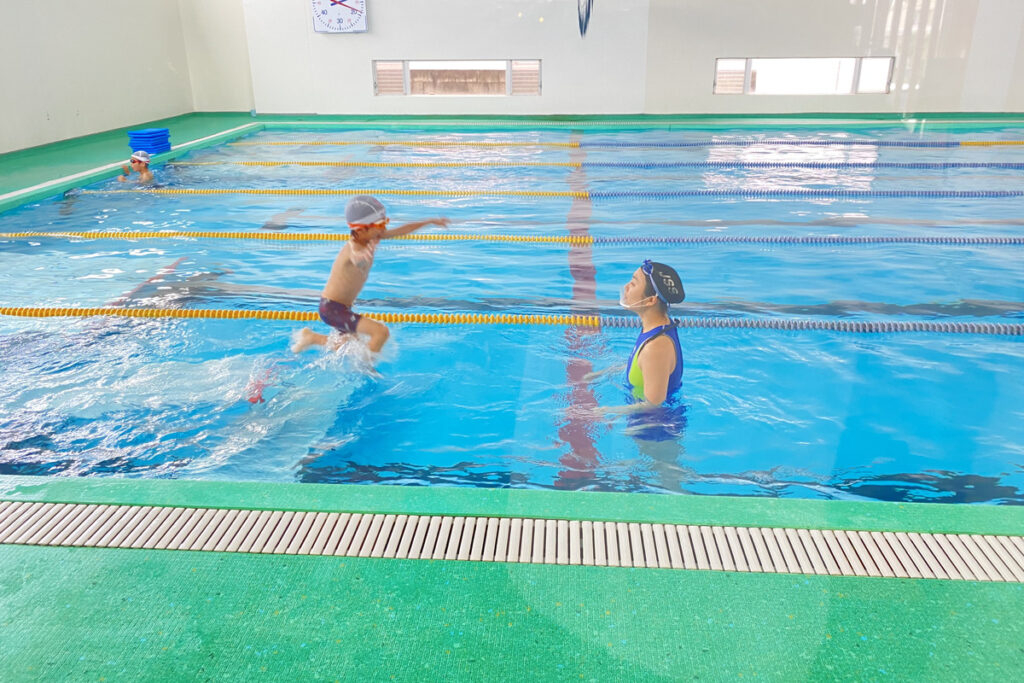 スイミングスクールでコーチに向かって飛び込むAKASHIの姿