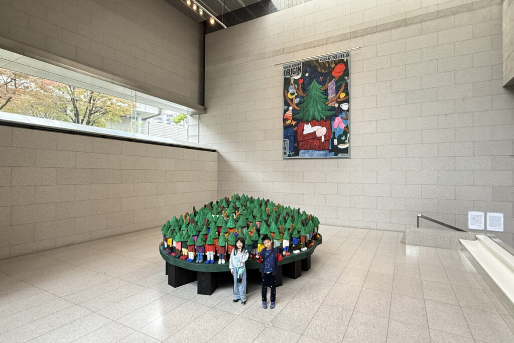 平子雄一展の会場で、カラフルな立体作品の前に立つAKASHIとRIRI。岡山県立美術館にて撮影。