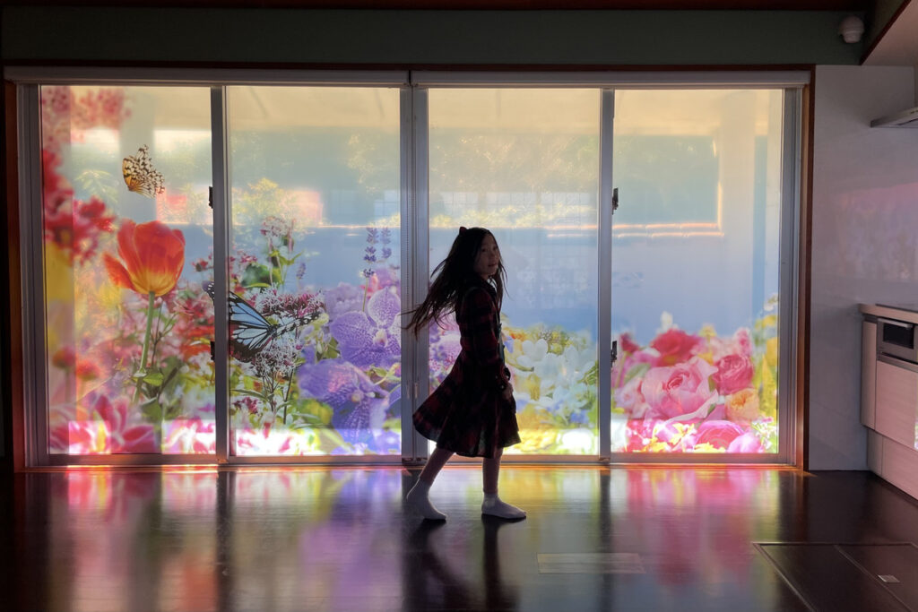 蜷川実花展の色鮮やかな作品を背景に美術館内を歩くRIRI