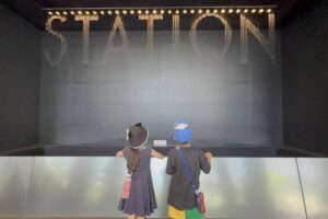 大阪駅の水の時計を見つめるAKASHIとRIRI
